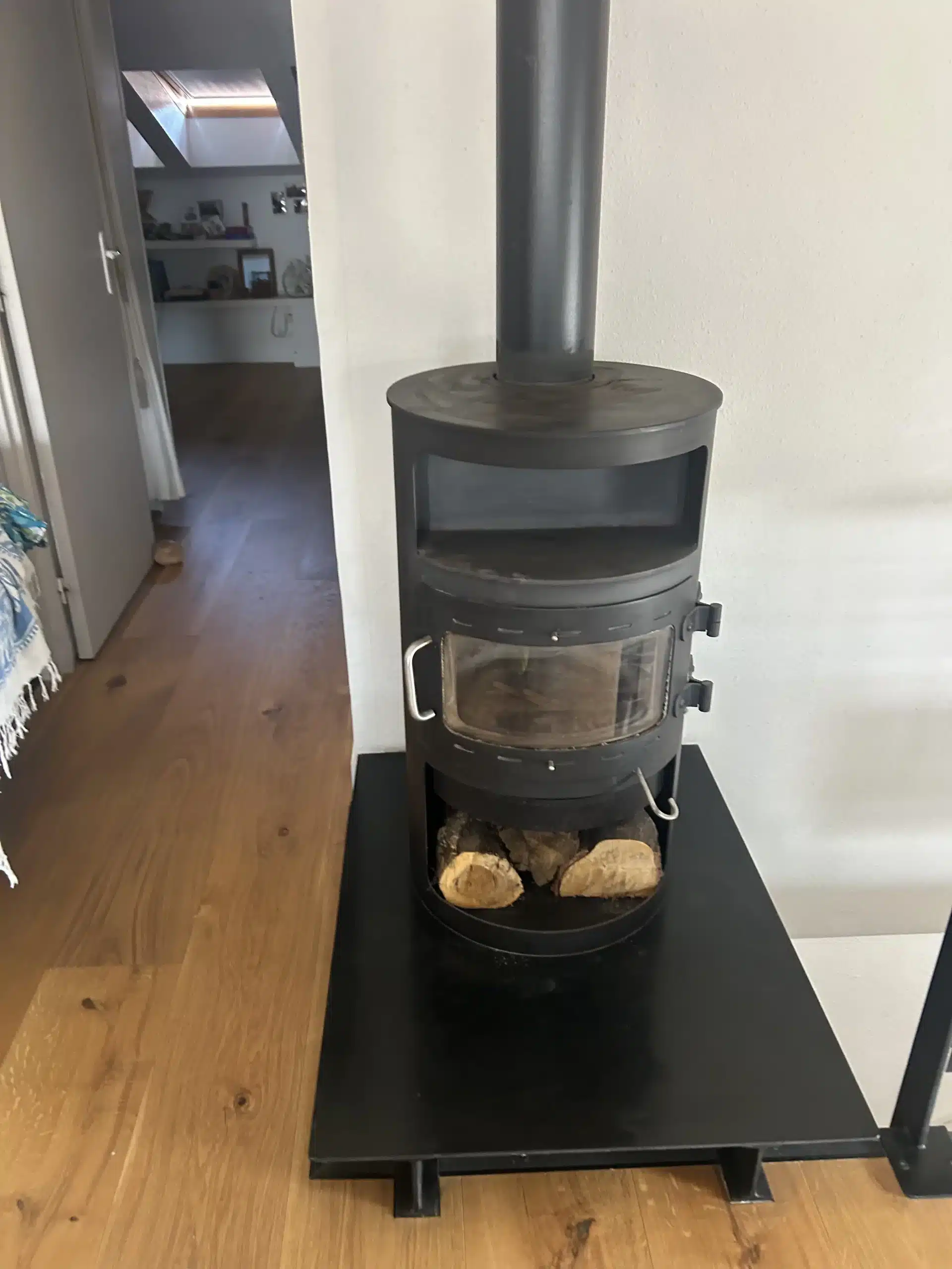 Poêle à bois avec conduit de cheminée dans une maison, installation nécessitant un ramonage régulier.